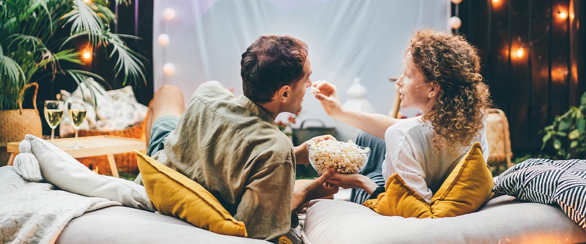 Couple feeding each other popcorn outside