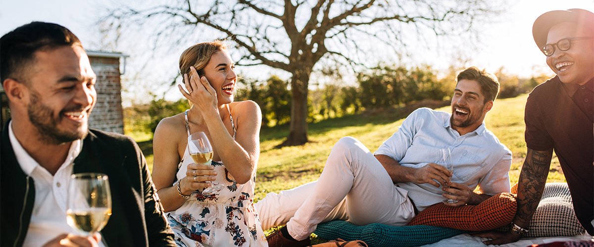 Friends laughing at backyard party sitting on pillows